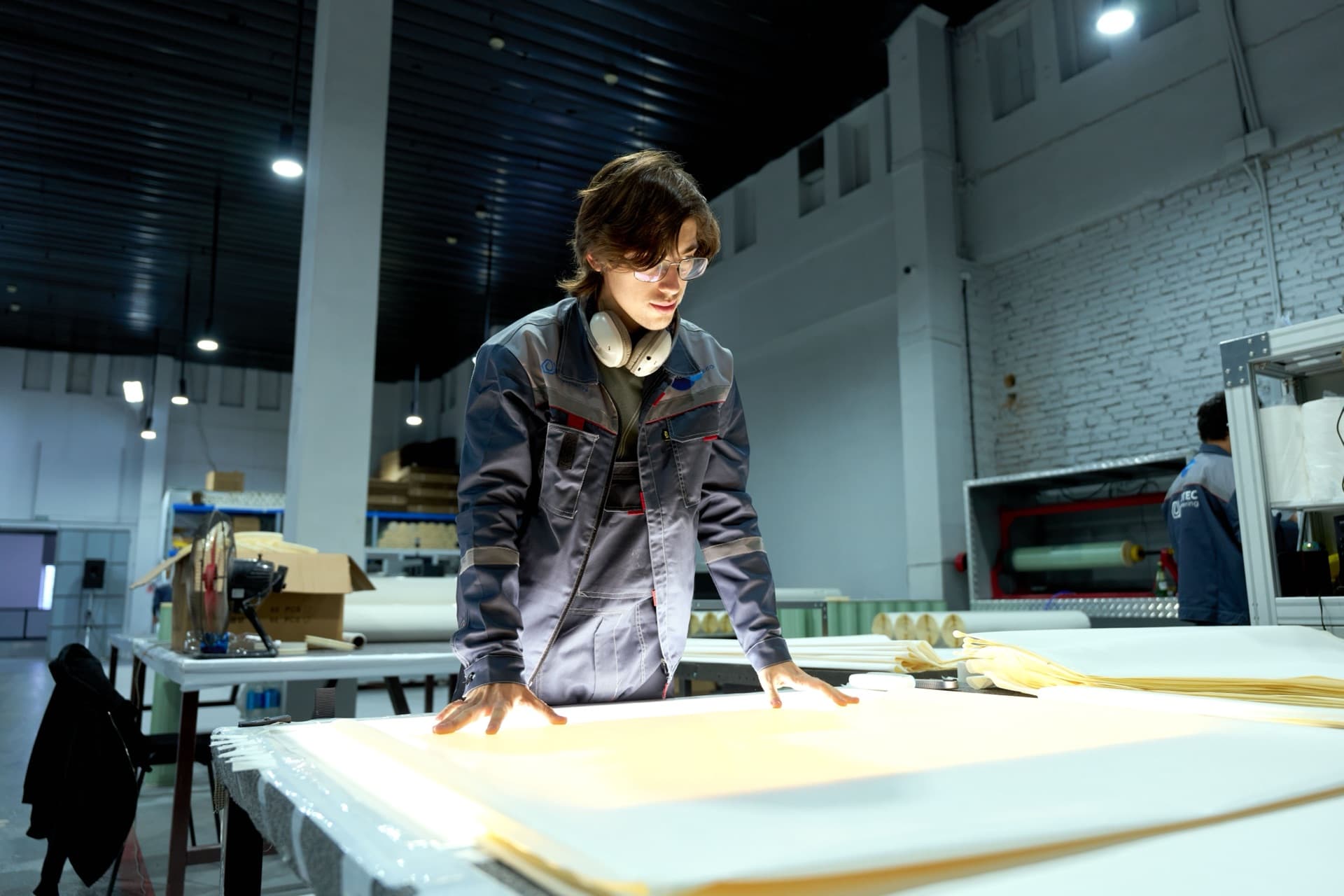 Tecnico che studia un progetto steso sul banco, dentro lo stabilimento