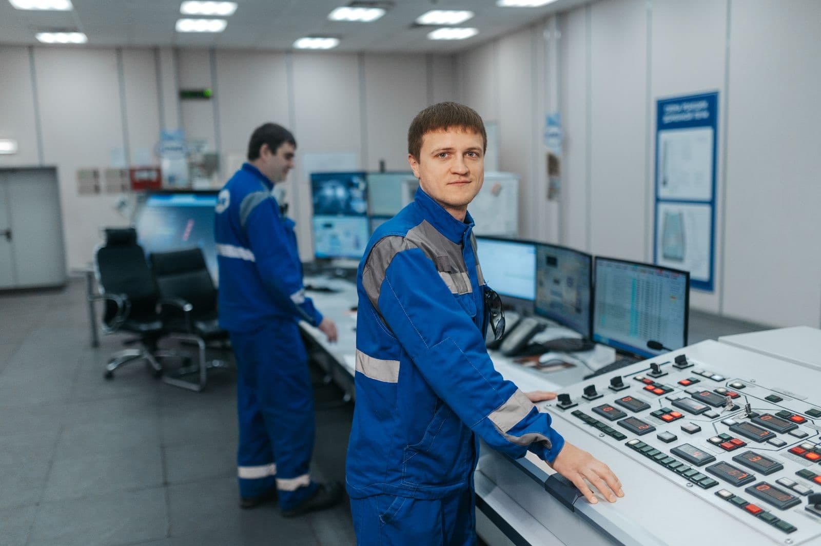 Sala controllo industriale: operatori tra pannello di comando e dashboard SCADA — integrazione IT/OT dalla macchina alla decisione.